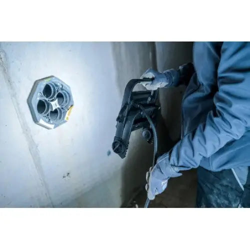 Arbeidslys LED JARO 4060 M i bruk, lyser opp betongvegg mens person bruker elektroverktøy ved installasjonsboks.