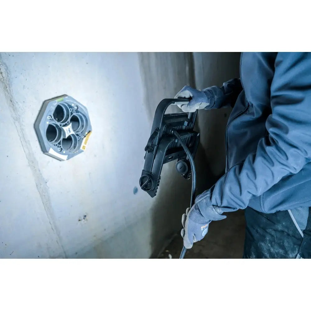 Arbeidslys LED JARO 4060 M i bruk, montert ved betongvegg mens en person arbeider med elektrisk verktøy.