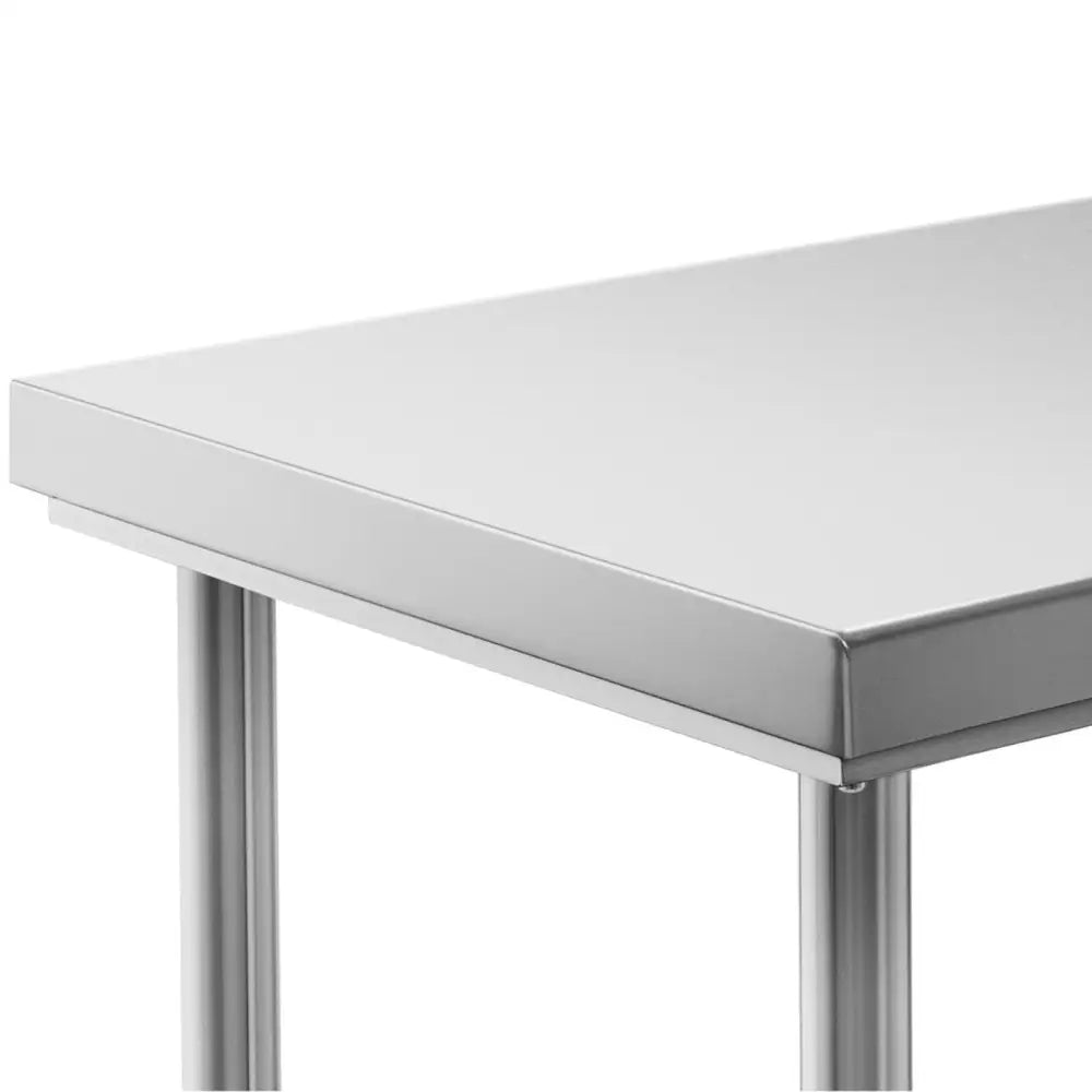 Arbeidsbenk i rustfritt stål, nærbilde av hjørne med glatt bordplate og runde ben, sett fra siden.