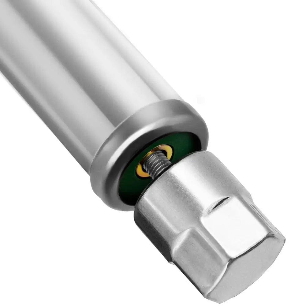 Sølvfarget sylinder med metallmutter og gjenge, grønne og gylne detaljer synlige i hylsen fra siden.