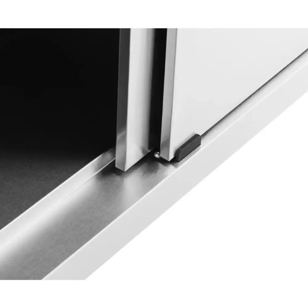 Skyvedør i rustfritt stål på arbeidsbord, detalj av skinne og mørk stopper nederst til høyre.