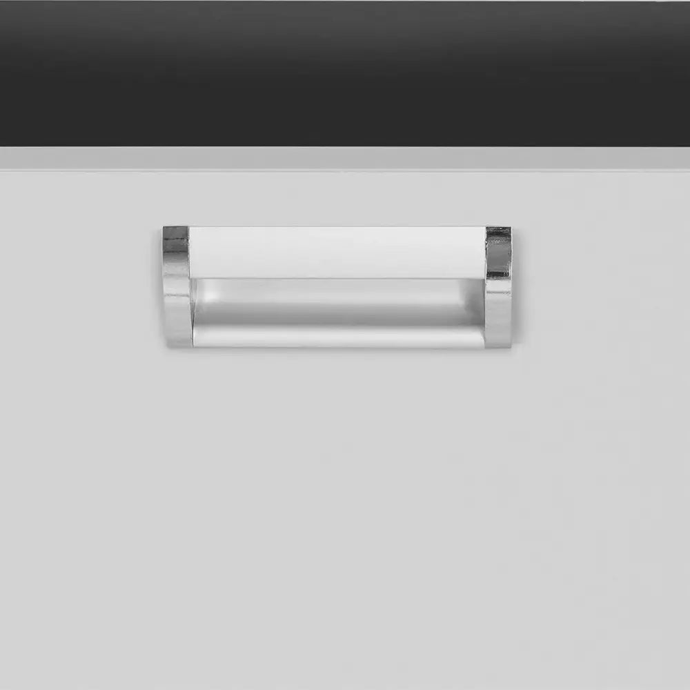 Metallhåndtak i sølv på arbeidsbordets lys front, detaljert nærbilde med mørk bordplate øverst.