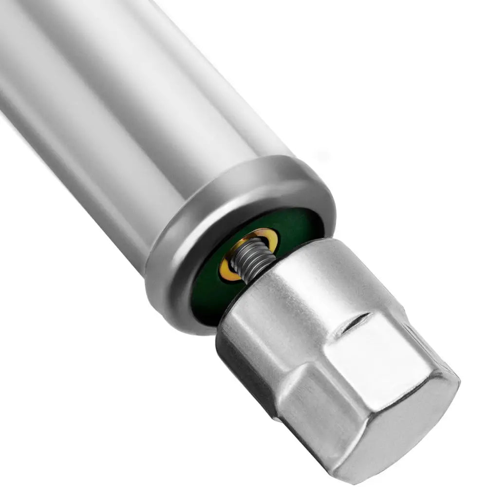 Nærbilde av sølvfarget gjengestuss med sekskantet ende, detaljer i grønt og messing for arbeidsbord.