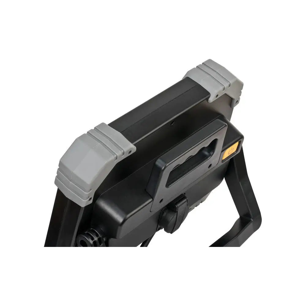 Arbeidslys LED DINORA, skrå oversikt som fremhever bærehåndtak, gul knapp og robust deksel i sort og grått.