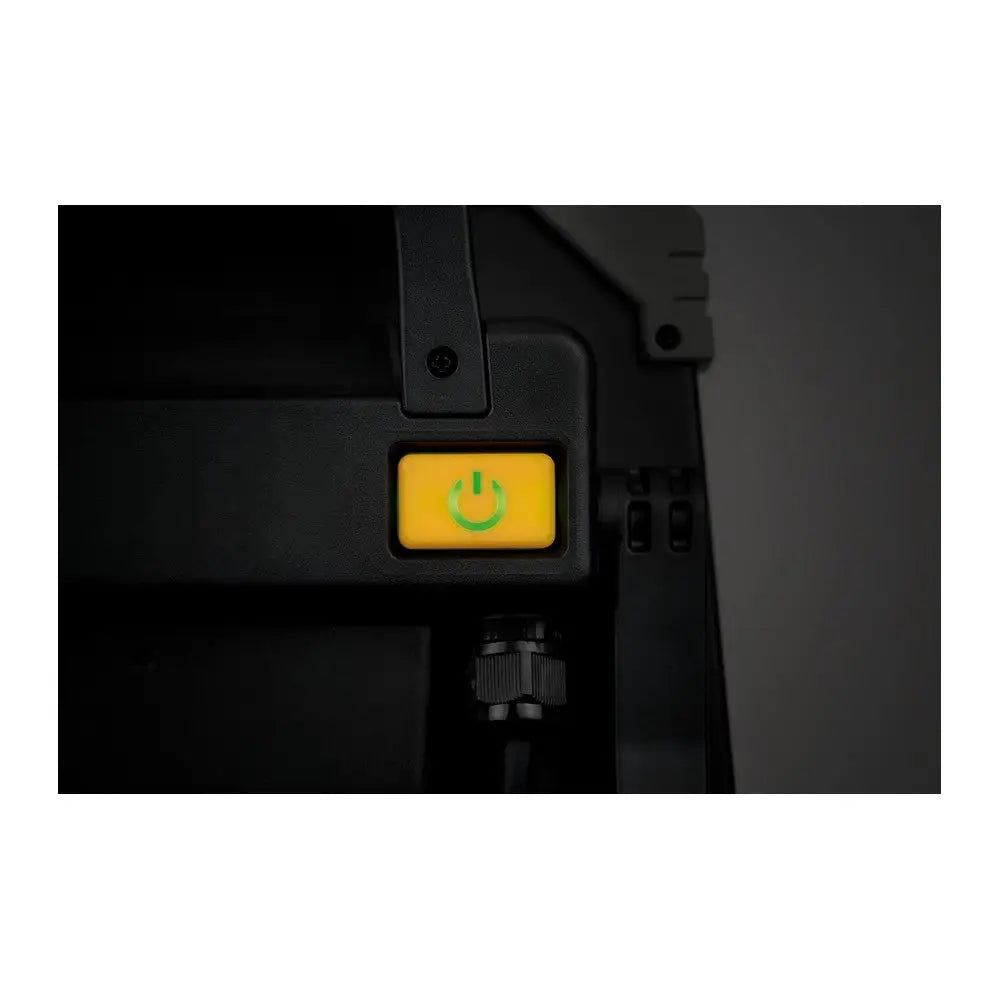 Arbeidslys LED DINORA, nærbilde av gul av/på-knapp med grønt symbol på svart plastpanel.