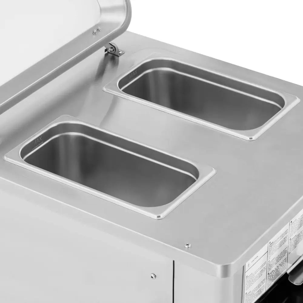 Automatisk iskremmaskin, nærbilde av to tomme stålkammer med åpne lokk og avrundede kanter sett ovenfra.