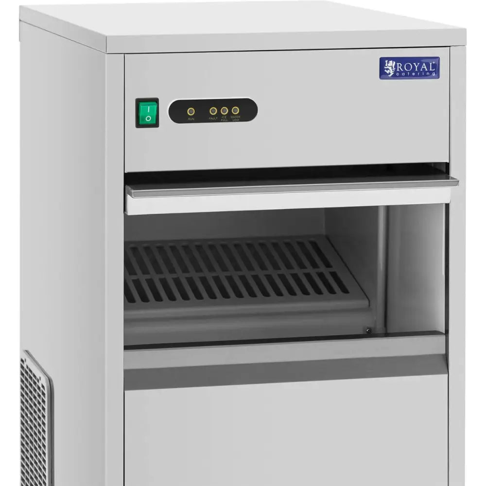 Automatisk ismaskin, skråvisning med synlig kontrollpanel, grønn av/på-knapp og åpen frontluke med rist.