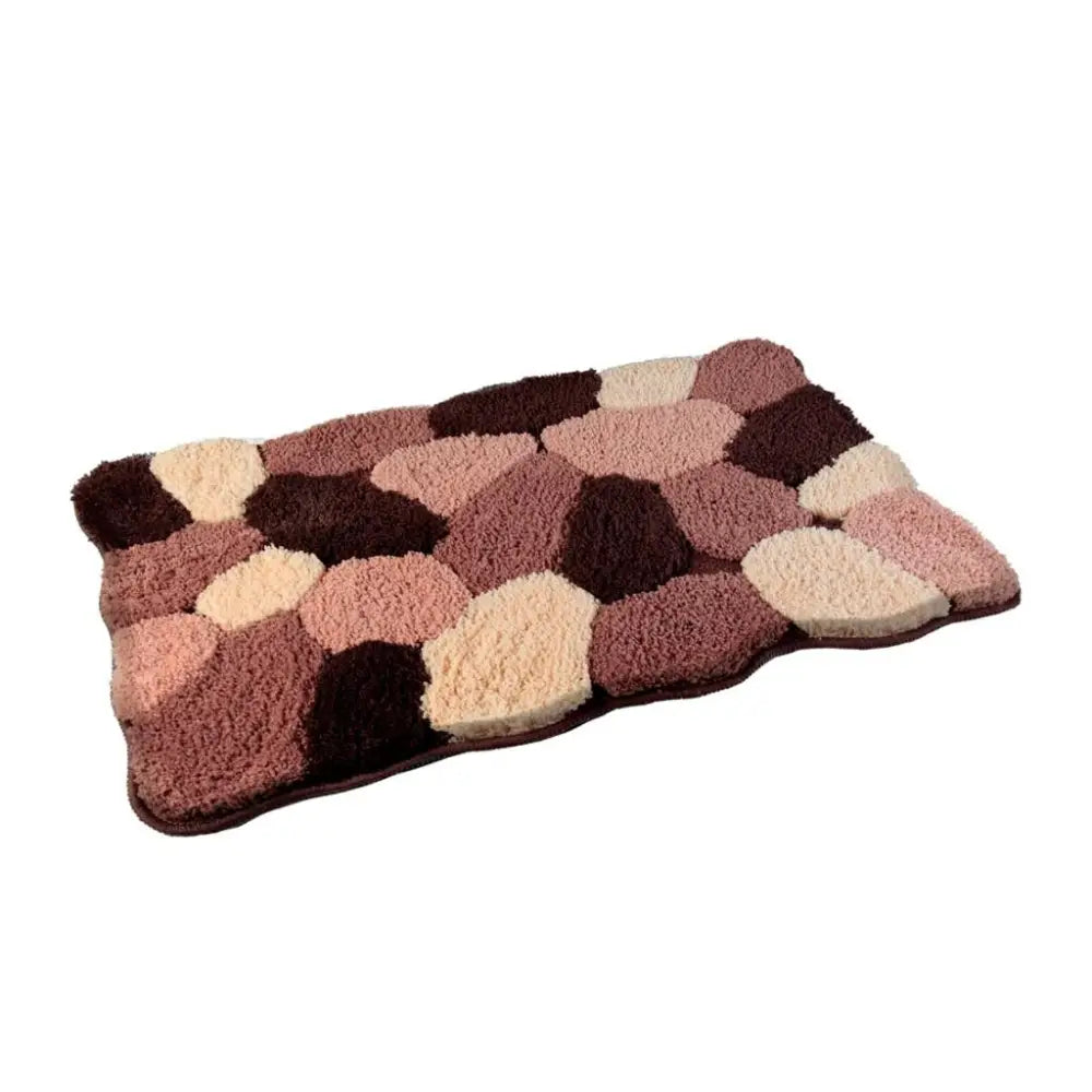 Baderomsmatte med flekkete mønster i rosa, beige og brunt, sett skrått ovenfra med ujevne kanter.