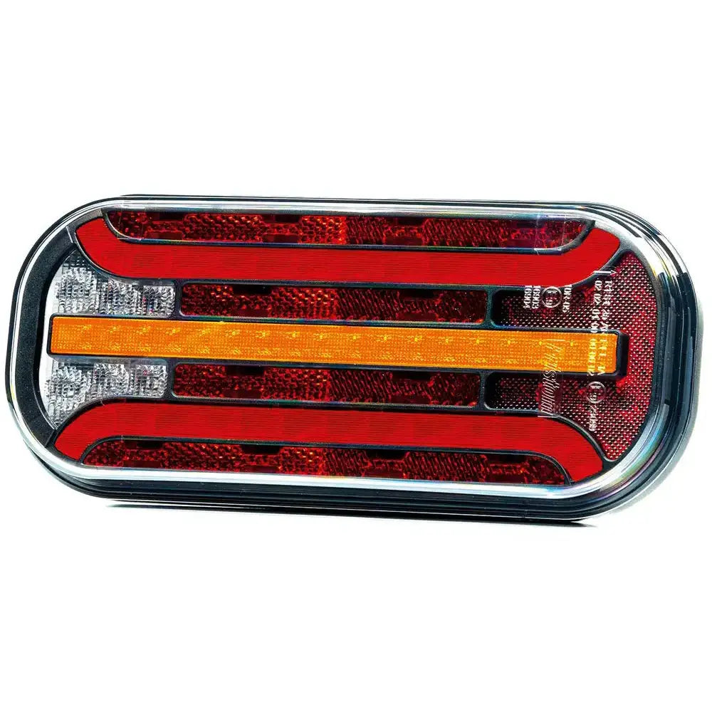 Baklys tilhenger Fristom FT-230, frontbilde med røde, gule og hvite felter i kromramme på hvit bakgrunn.