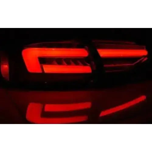 Baklykt Audi A4 B8 12-15 sedan med røde LED-striper og reflekser, sett bakfra i mørket.