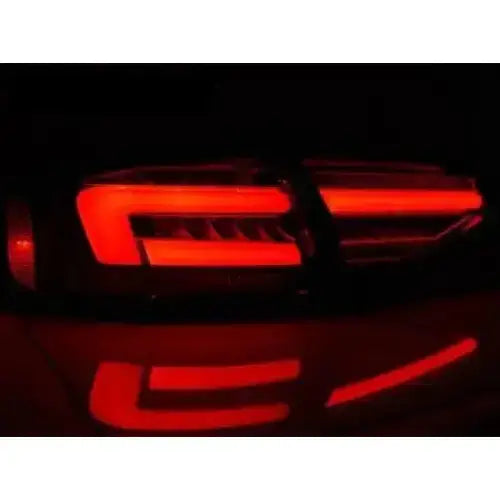 Baklykt Audi A4 B8 LED, skrå bakfra i mørket med rødt geometrisk lysmønster og refleksjon.
