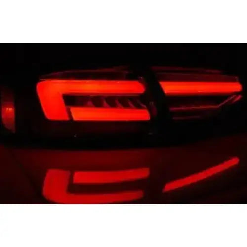 Baklykt Audi A4 B8 12-15 sedan med røde LED-striper, skrå vinkel i mørket, refleksjon under.