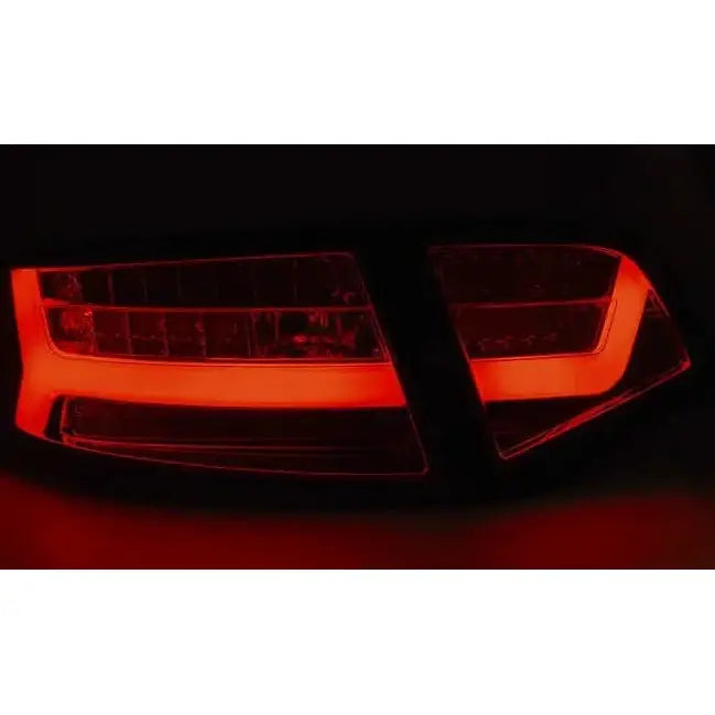 Baklys Audi A6 08-11 Sedan Black Smoke med opplyste røde LED-barer sett bakfra i mørket.