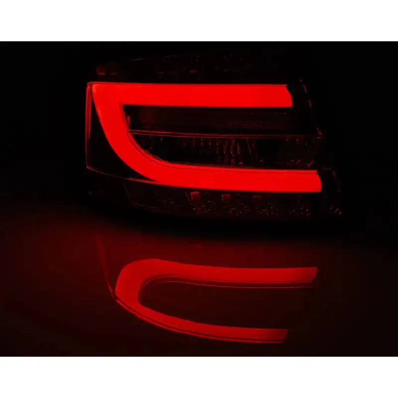 Baklykt Audi A6 C6 Sedan LED i svart og rødt med C-formet rødt lys sett fra skrå vinkel.