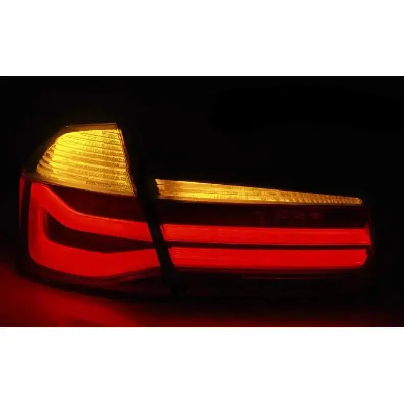 Baklamper Bmw F30 11-15 LED med røde og oransje lysfelt, skrå bakside i mørkt miljø.