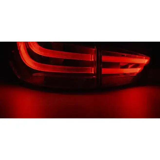 Baklys Bmw X1 E84 LED med horisontale røde striper, sett bakfra i mørket.