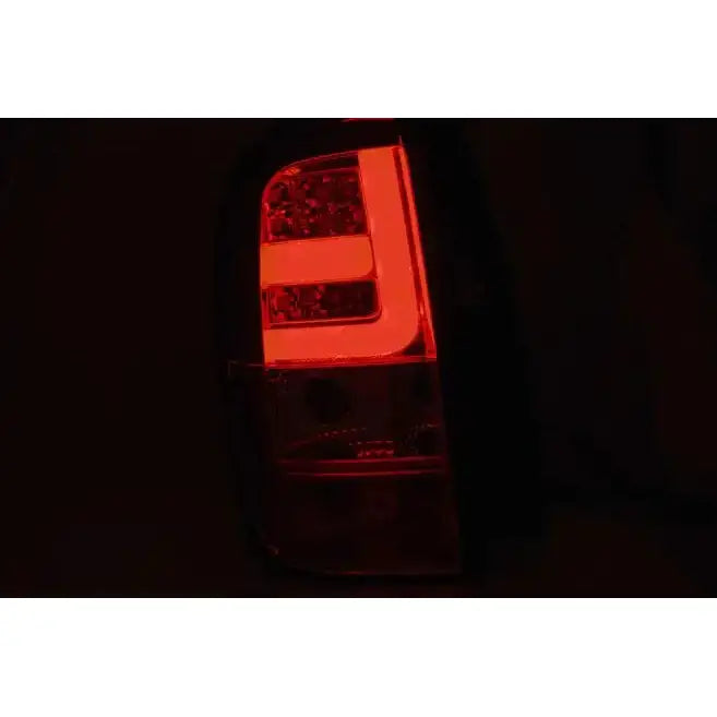 Baklys Dacia Duster LED Bar Smoke med rød L-formet lyssignatur sett fra skrå vinkel i mørket.