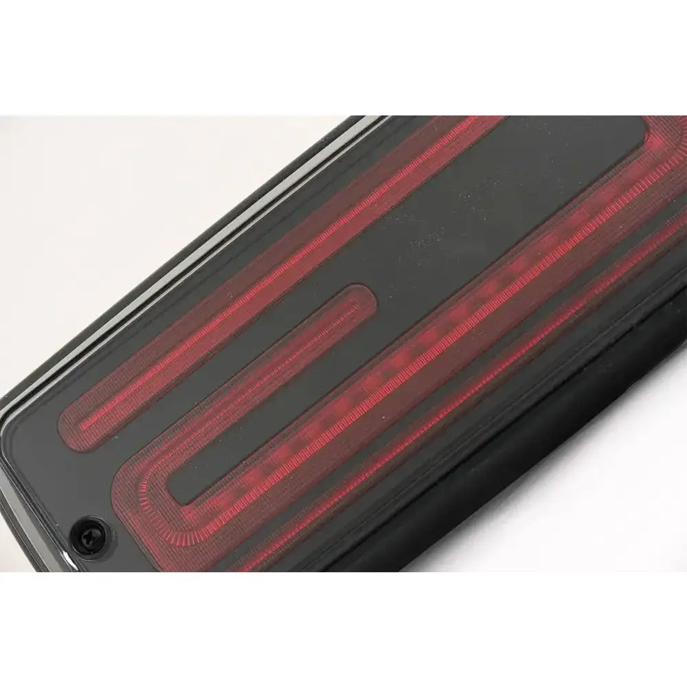 Baklys Dynamic Smoke Mercedes G-Klasse W463 med LED-stripe og skruedetalj, nærbilde fra skrå vinkel.