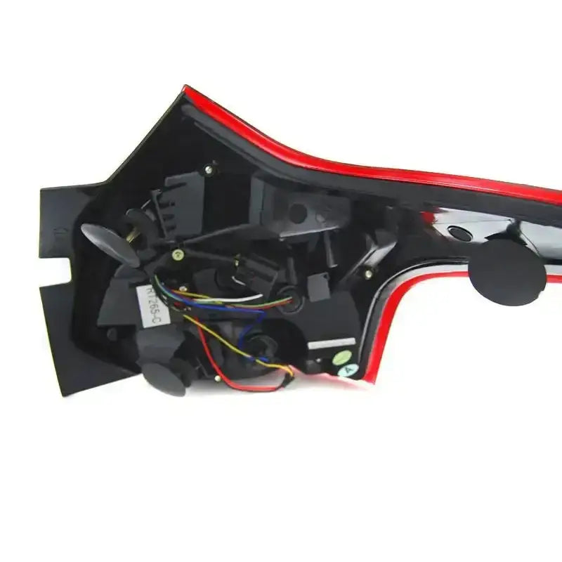 Baklamper Ford Focus 3 nærbilde av innsiden med ledninger, kontakter og sorte plastdetaljer med rød kant.