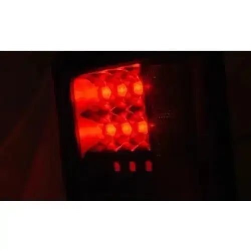 Baklys Jeep Wrangler JK LED Smoke med røde dioder, nærbilde fra skrå vinkel mot mørk bakgrunn.