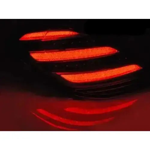 Baklys Mercedes S-Klasse W222 med tre røde LED-striper, sett skrått i mørket med refleksjon.