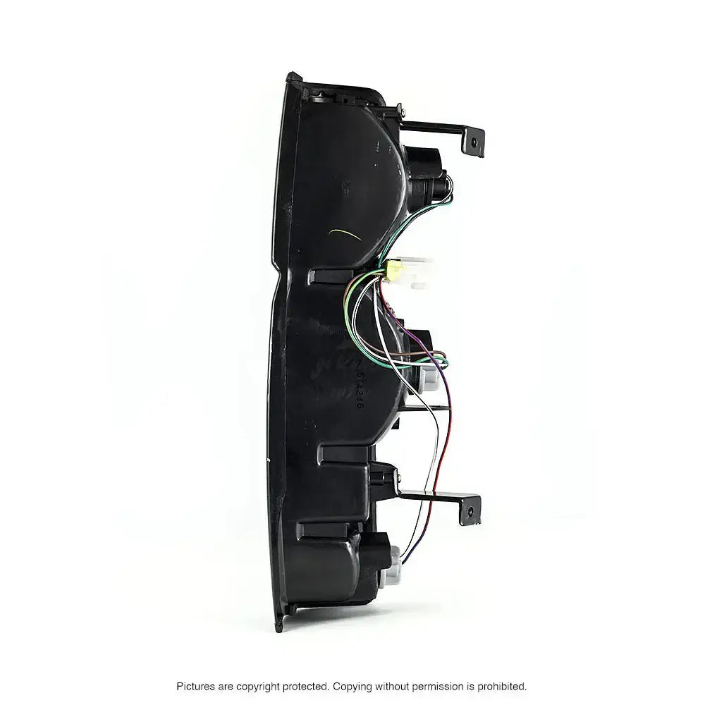 Baklykt Nissan Pickup D21 85-98 med synlige fargede ledninger og koblinger, sidevisning mot hvit bakgrunn.