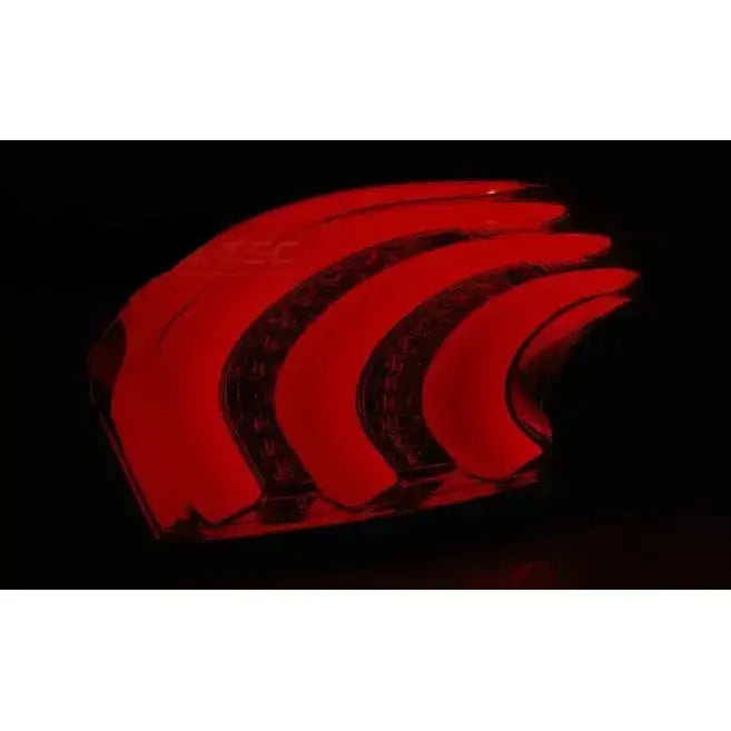 Baklys Peugeot 208 LED baklykt med buede røde LED-striper, sett fra skrå vinkel mot mørk bakgrunn.