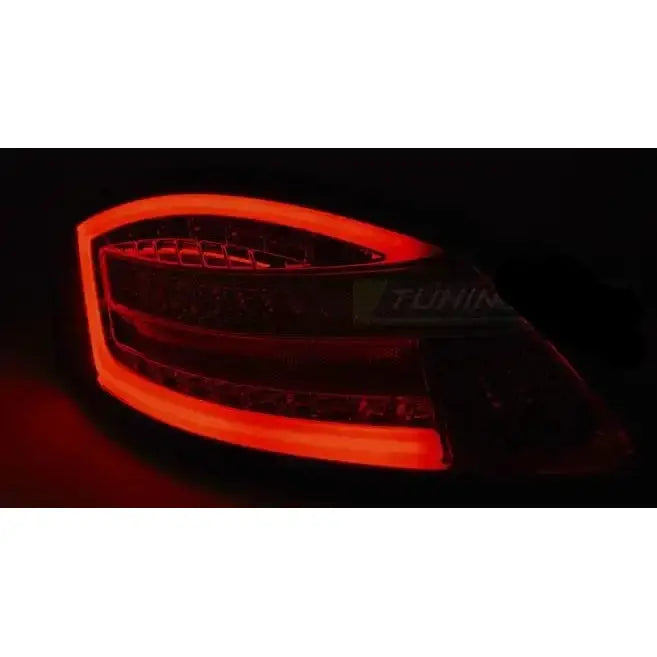 Baklys Porsche Boxster 987 LED med rød ramme og moderne buet design fotografert i mørket.