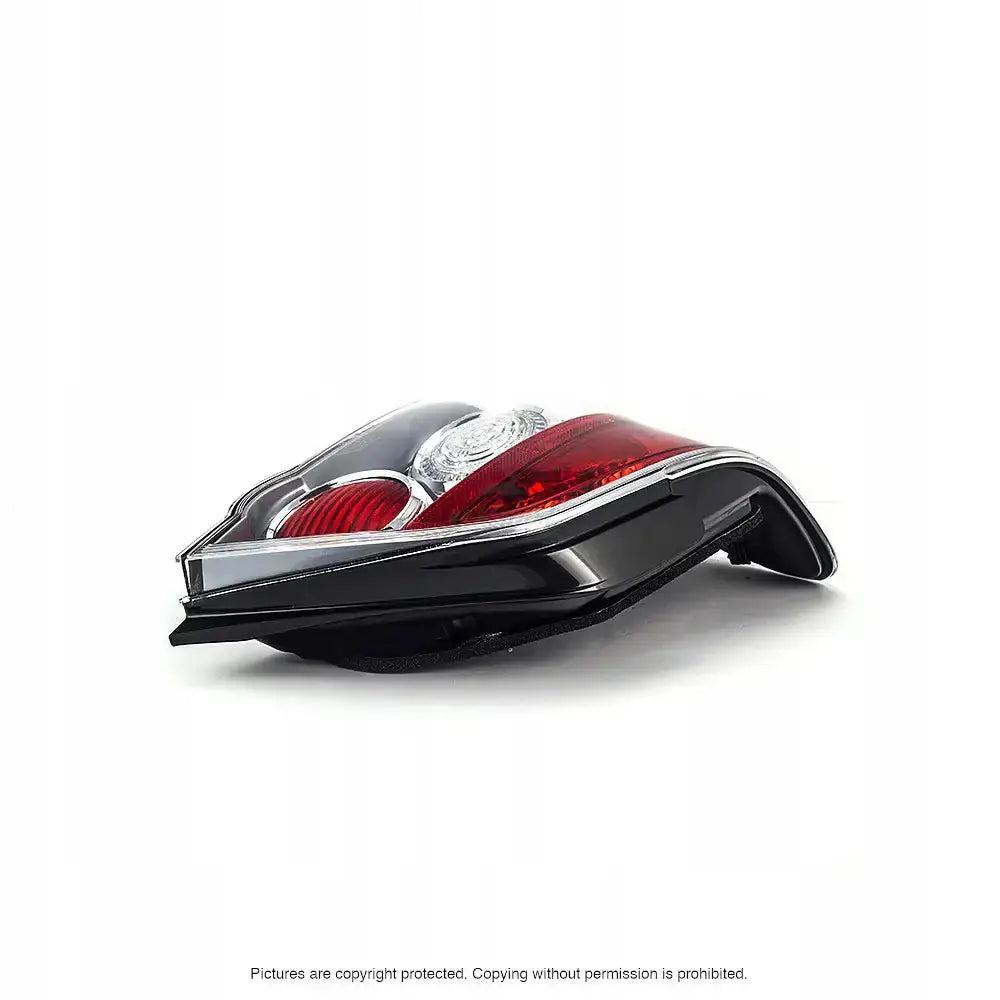 Baklys Subaru Impreza II 01-07 med sort, rød og klar plast, sett fra siden på lys bakgrunn.