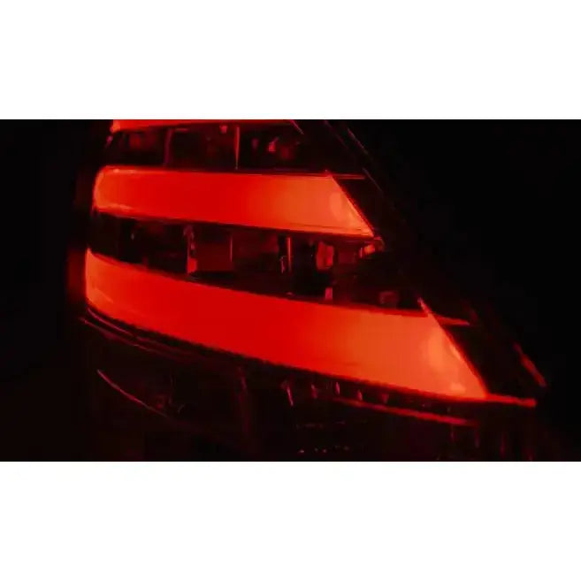 Baklamper Suzuki Swift IV med to horisontale røde LED-striper lyser mot mørk bakgrunn.