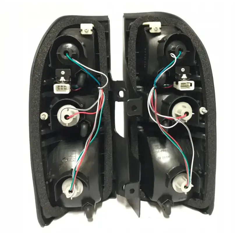 Baklykt Toyota Land Cruiser 90 J9 svart plastdeksel med tre lyssokler, ledninger og skumlist bakside.