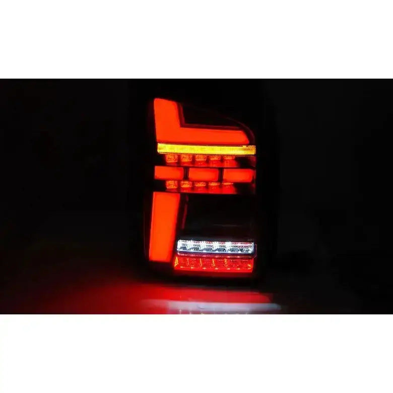 Baklykter Volkswagen T6.1 20- LED Black med opplyste røde og hvite felt, oransje blinklys og geometrisk design.