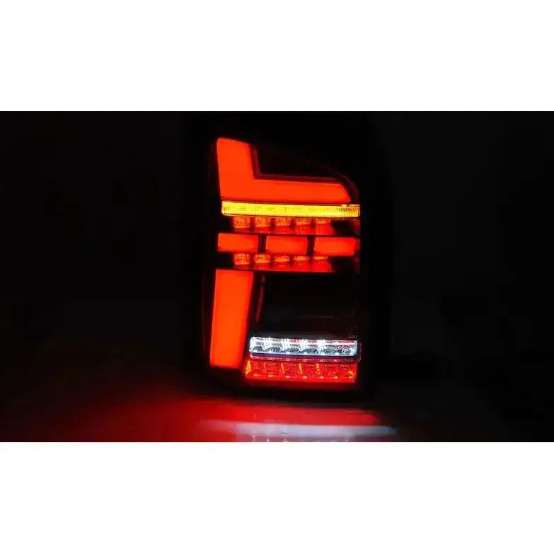 Baklykter Volkswagen T6 15-19 LED Black med røde og hvite lyssegmenter opplyst i mørket.