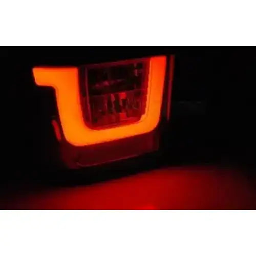 Baklykt Vw T4 90-03.03 med L-formet LED-bar, rød glød sett fra skrå vinkel i mørket.