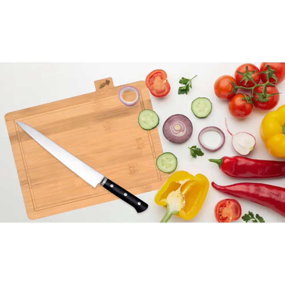 Bambus Skjærebrett Dori med stor kjøkkenkniv, friske grønnsaker og oppskårne skiver på lyst trebrett.