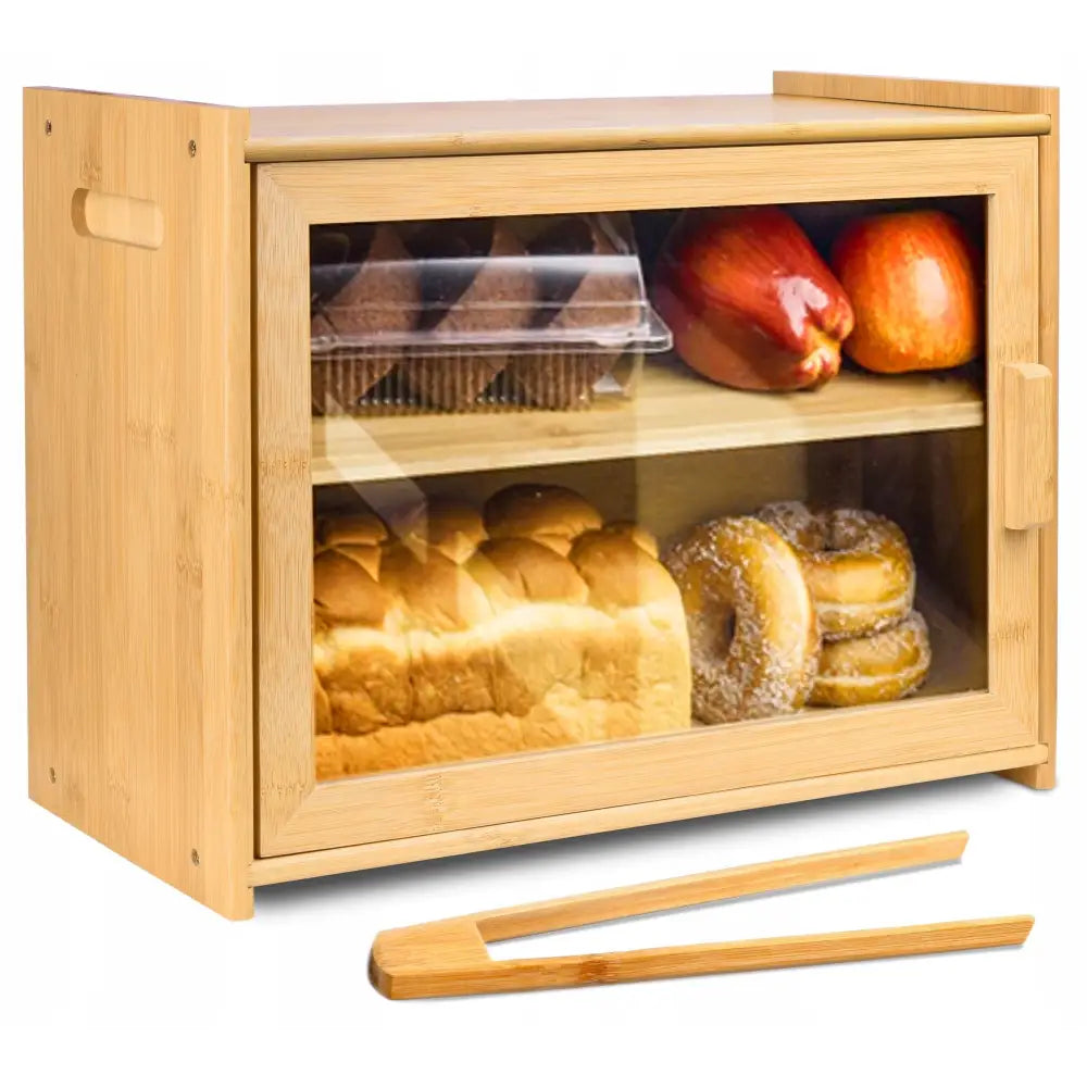 Bambus brødboks med gjennomsiktig dør, brød og frukt synlig inni, trepinsett foran på benken.