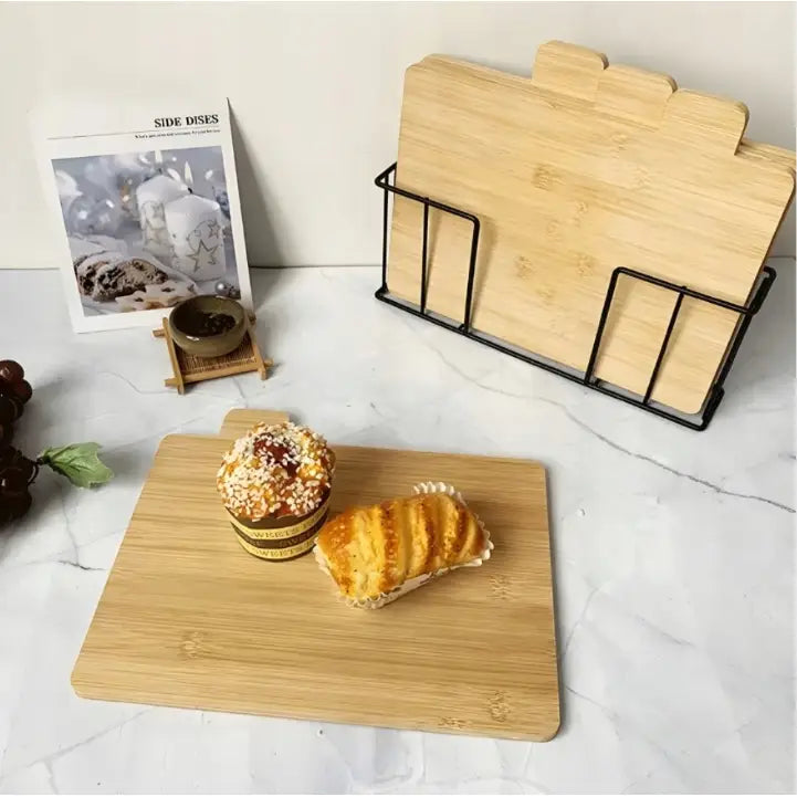 Bambuskjøkken skjærebrett sett, fire brett i stativ, nærbilde med muffin og bakverk oppå det fremste.