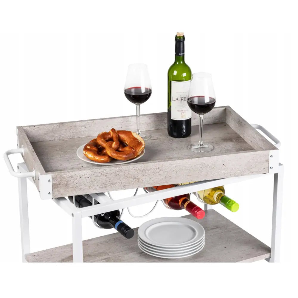 Trillebord med hyller og flaskeholder, skråvisning med vinflasker, vinglass og serveringsfat på lys grå overflate.