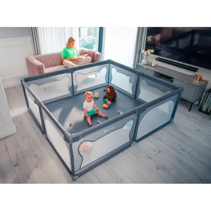 Lionelo Willow XL barnelekegrind i grått, skrå vinkel med barn og leker i lys stue med mesh-sider.