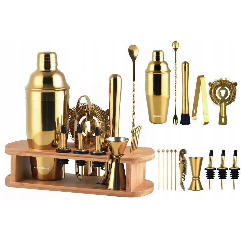 Bartender sett i gullfarget metall med shaker, målebeger, røreskje og sil arrangert på lyst trebord.