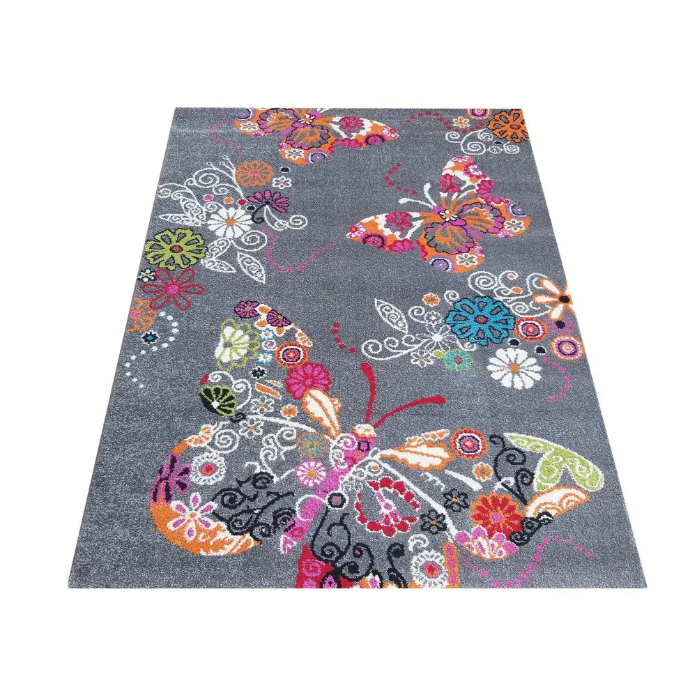 Bella 114 grått teppe 160 x 220 cm, sett skrått ovenfra med fargerike sommerfugler og blomster.