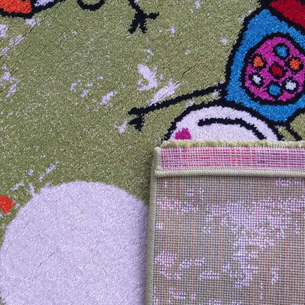 Bella 117 grønt barneteppe, nærbilde med synlig bakside og kantforsterkning i et fargerikt figurmønster.