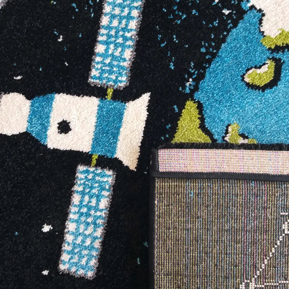 Bella 120 Tepe, nærbilde av romfartmotiv med satelitt og jordklode, oppbrettet hjørne viser teppets underside.