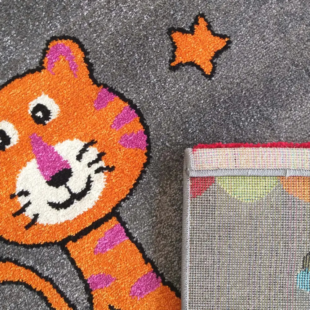 Bella grå teppe 160 x 220 cm, nærbilde av oransje tiger, stjerne, grå bakside og sydd kant.