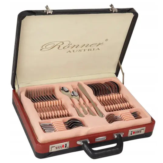 Bestikksett med roséfargede håndtak, sortert i åpen koffert med myk, lys rosa innmat, skrå forfra.