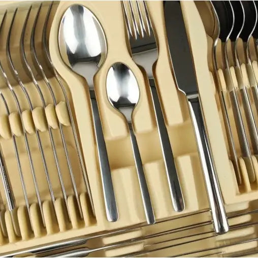 Bestikksett i rustfritt stål, oversiktsbilde ovenfra med skjeer, gafler og kniver sortert i beige innsats.