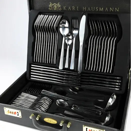 Bestikksett Monica, 72 deler i rustfritt stål, lagt ut i sort koffert med gullfargede detaljer, sett fra skrå vinkel.