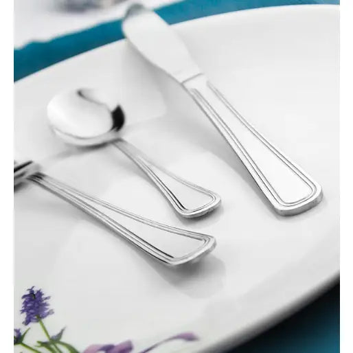 Bestikksett i rustfritt stål med doble rillede kanter, arrangert på tallerken med blomsterdekor.