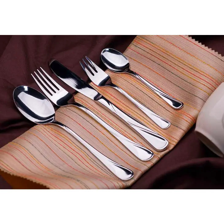 Bestikksett i blankt rustfritt stål, fem deler arrangert på stripet serviett med varme tekstiltoner bak.