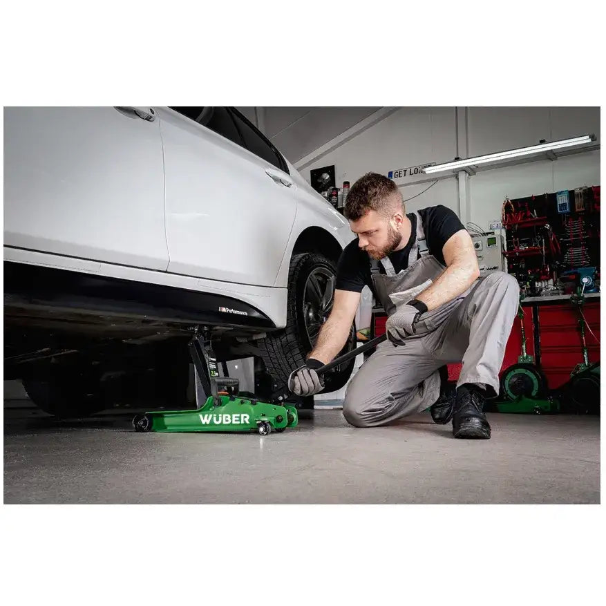Biljekk Lavprofil 2,5t, sidebilde hvor mekaniker løfter hvit bil med grønn jekk i verkstedmiljø.